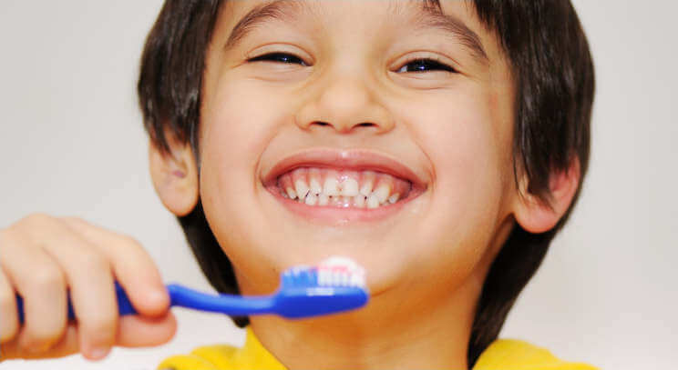 child smiling brushing his teeth