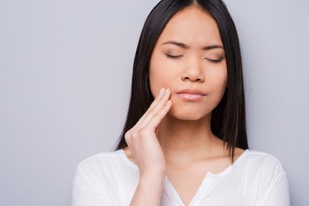 woman holding her mouth from tooth pain