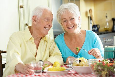 couple with dentures smiling while eating