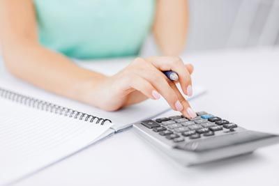 Woman using a calculator beside a notebook